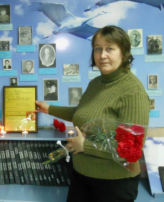 Светлана Морева с орденом деда у стенда с его фотографией. 2016.